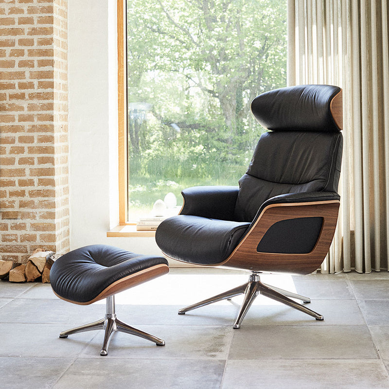 flexlux clement recliner chair and footrest in savoy plain black leather. sitting in front of garden window.